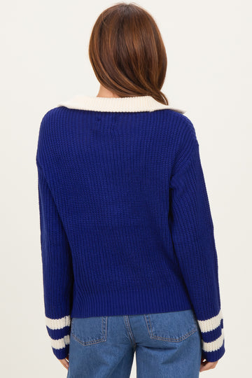 woman wearing a back view of a blue ribbed sweater with a white collar and striped cuffs
