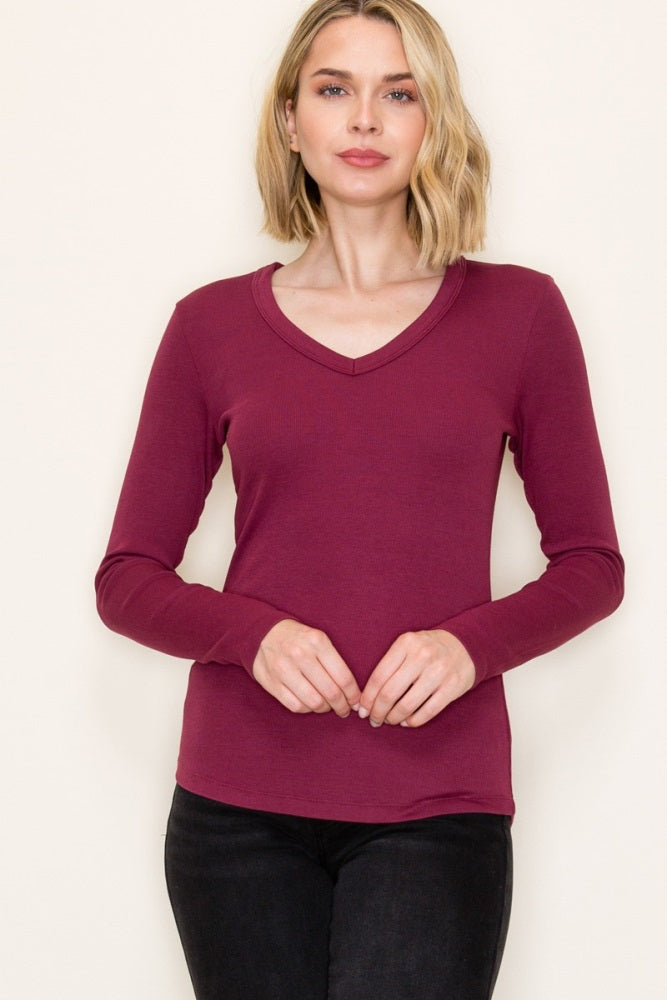 woman wearing a burgundy long sleeve v-neck top with a fitted style and relaxed fit