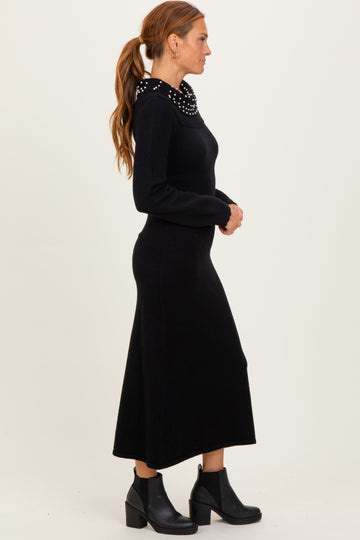 woman wearing a black long sleeve sweater dress with a beaded collar and ankle boots