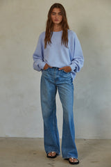 woman wearing a light purple oversized sweater and high-waisted flared jeans with hands in pockets