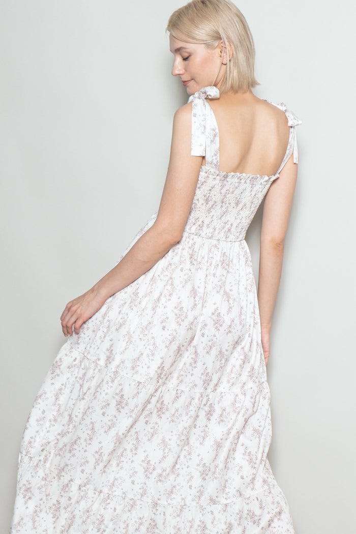 woman wearing a light pink floral maxi dress with tie straps and smocked back detail, photographed from the back