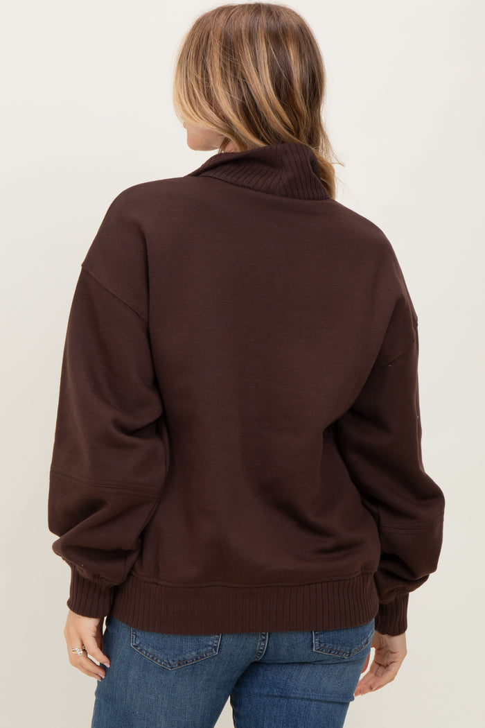 woman wearing a brown oversized sweatshirt with a high collar and balloon sleeves, viewed from the back