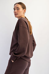 woman wearing a dark brown oversized sweatshirt with dropped shoulders and minimalistic design