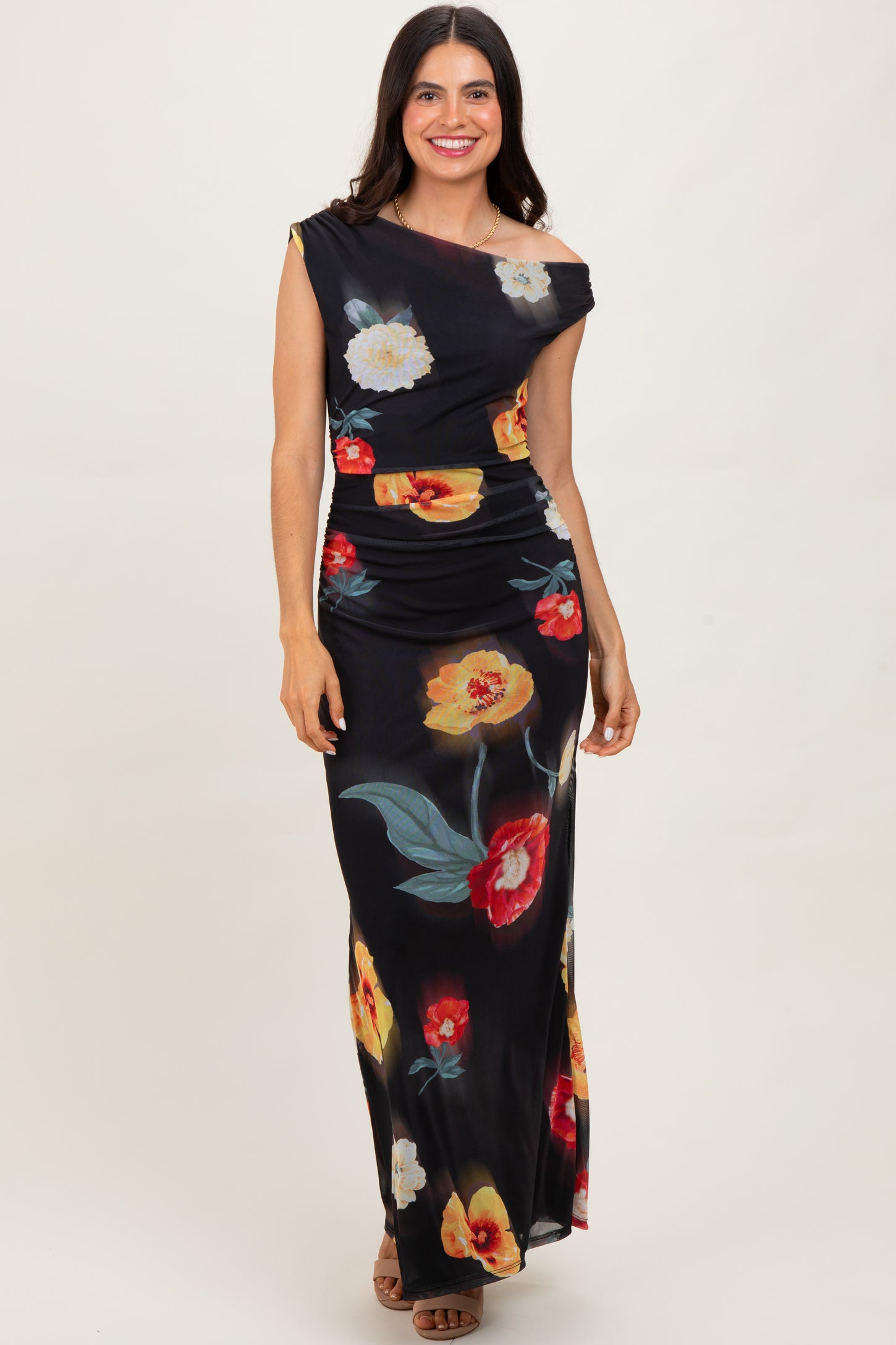 woman wearing a black off-shoulder maxi dress with colorful floral prints and a fitted waistline
