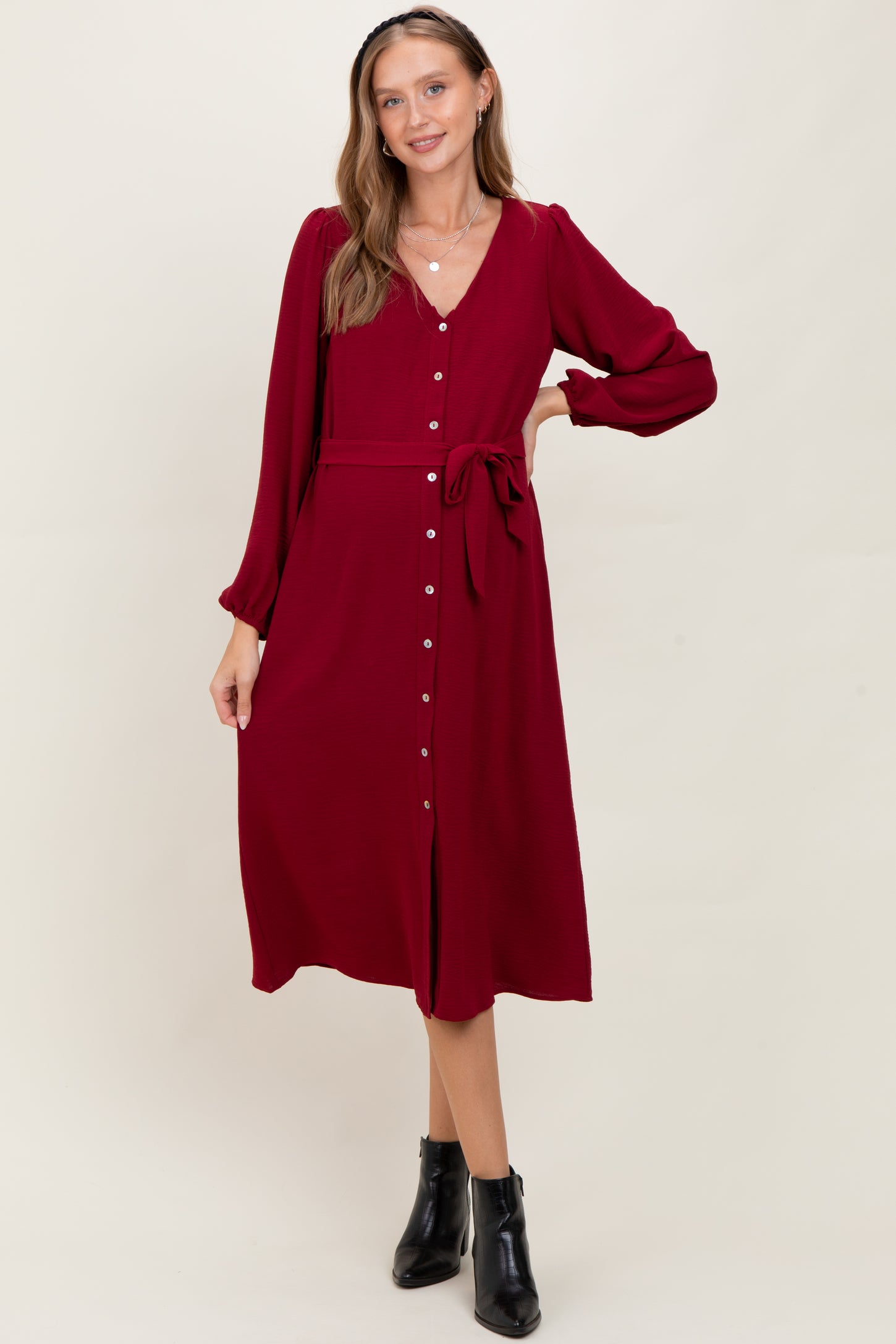 woman wearing a burgundy long sleeve maternity dress with button-down front and tie waist detail