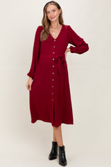 woman wearing a burgundy long sleeve maternity dress with button-down front and tie waist detail