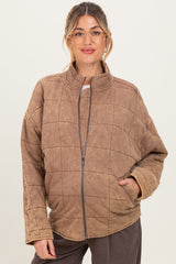 woman wearing a brown quilted maternity jacket with a zip front and side pockets, showing her baby bump