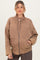 woman wearing a brown quilted maternity jacket with a zip front and side pockets, showing her baby bump