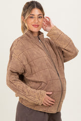 woman wearing a brown quilted maternity jacket and posing with her baby bump