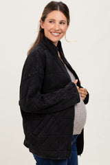 woman wearing a black quilted maternity jacket and grey sweater, showing her baby bump