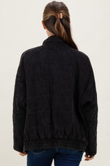 woman wearing a black quilted maternity jacket with a relaxed fit and elastic waistband, viewed from the back