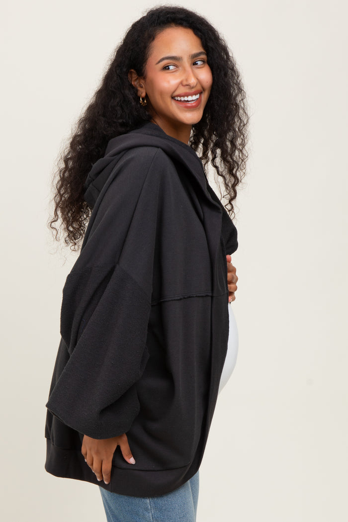 woman wearing a black maternity hoodie with oversized sleeves and a visible baby bump