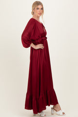woman wearing a burgundy long sleeve maxi dress with ruffle hem and waist detail