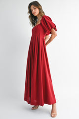 woman wearing a red puff sleeve maxi dress with a square neckline and pleated skirt