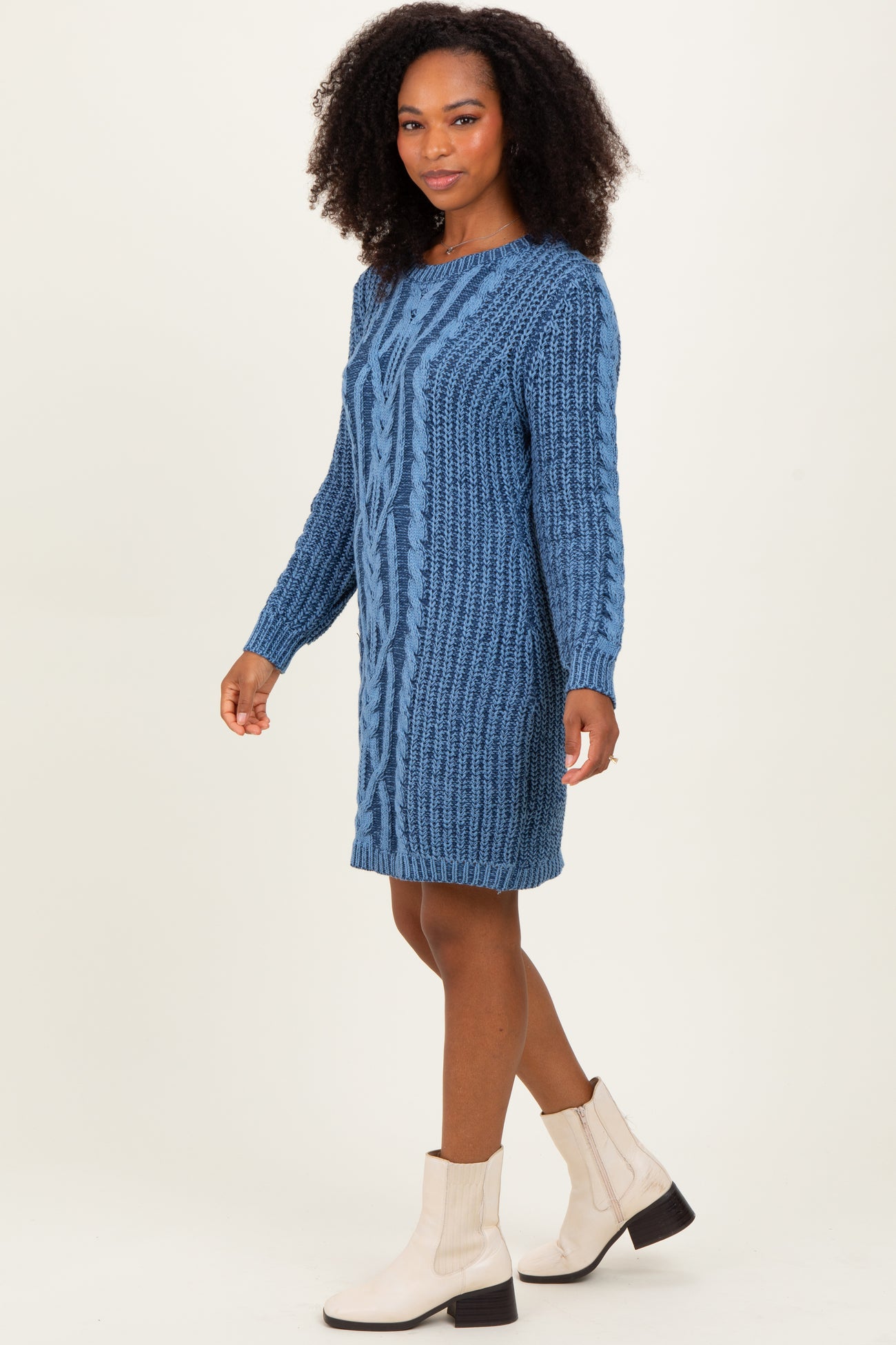 woman wearing a blue cable knit sweater dress with long sleeves and a loose fit, paired with ankle boots