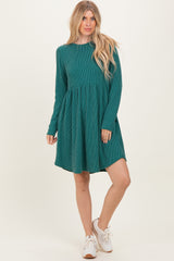 woman wearing a teal corduroy long sleeve dress with a flared skirt and white sneakers