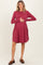 woman wearing a raspberry long sleeve maternity dress, holding her baby bump, with a flared skirt and ribbed texture