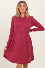 woman wearing a maroon striped maternity dress with long sleeves and a flared skirt, showing her baby bump