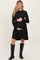 woman wearing a black ribbed maternity dress and holding her baby bump, paired with tall black boots