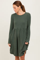 woman wearing a dark green long sleeve striped dress with a relaxed fit and gathered waist