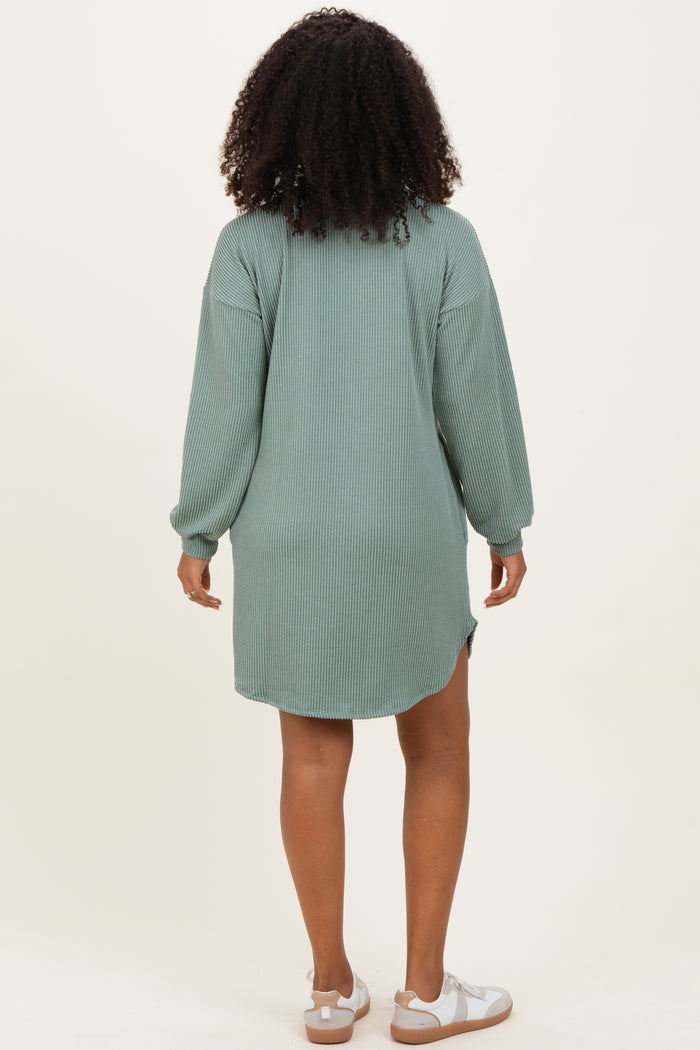 woman wearing a green ribbed long sleeve oversized dress with a high-low hem and white sandals