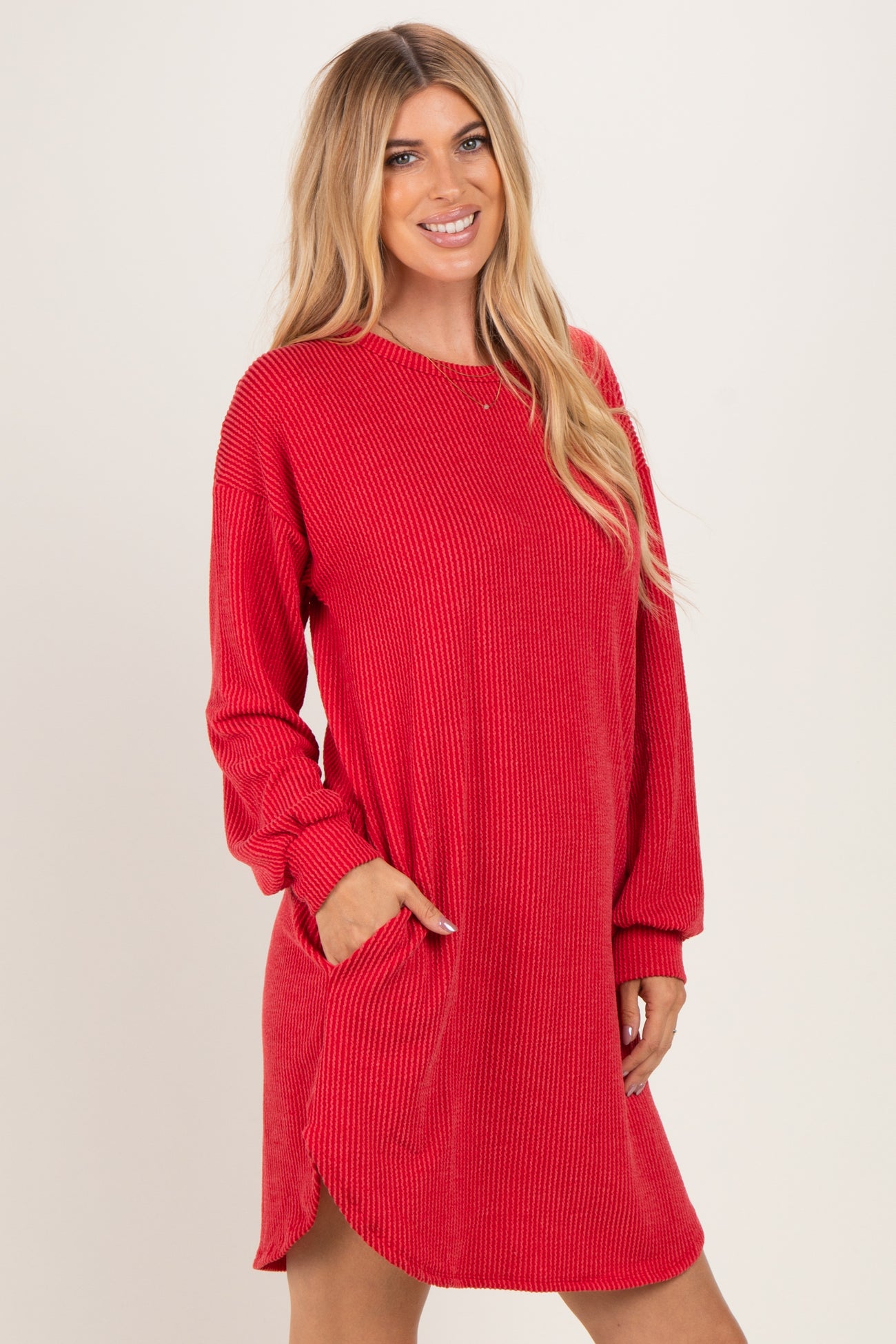 woman wearing a red ribbed long sleeve dress with side pockets and a relaxed fit
