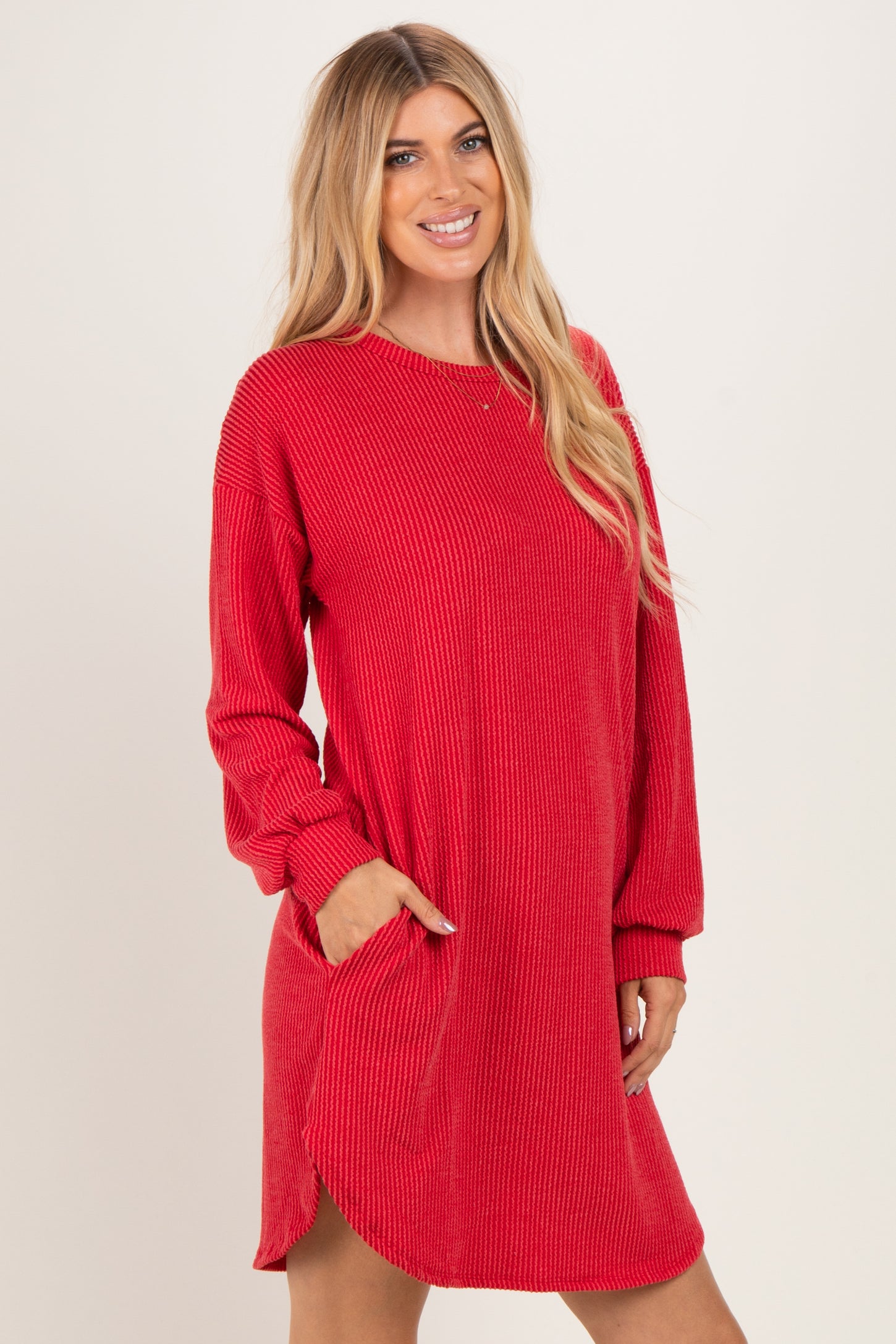 woman wearing a red ribbed long sleeve dress with side pockets and a relaxed fit