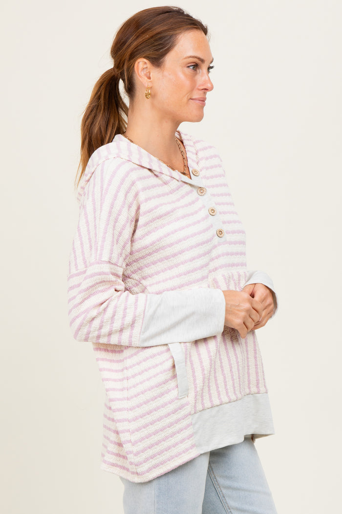 woman wearing a pink and white striped hooded sweater with button details and a contrasting gray bottom