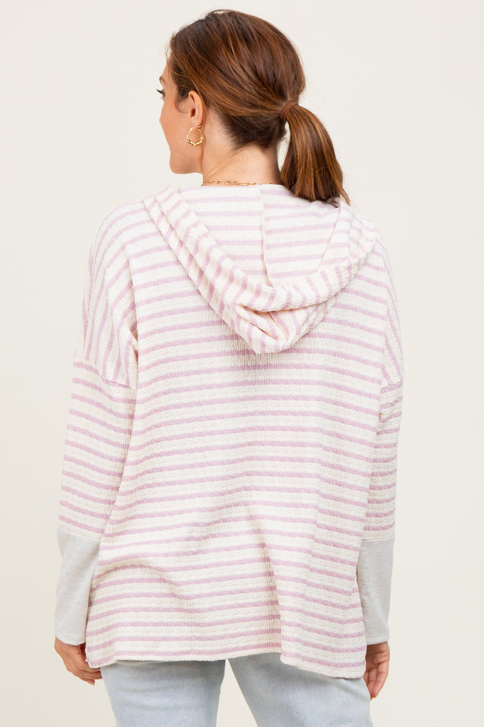 woman wearing a striped pink and white hoodie sweater, shown from the back, with a relaxed fit and a hood