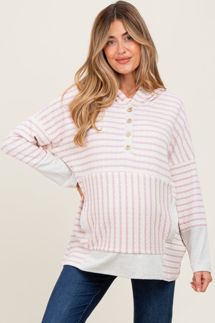 woman wearing a light pink and white striped maternity hoodie with buttons and a visible baby bump