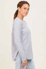 woman wearing a light gray long sleeve ribbed top with side slits and relaxed fit, paired with light blue jeans