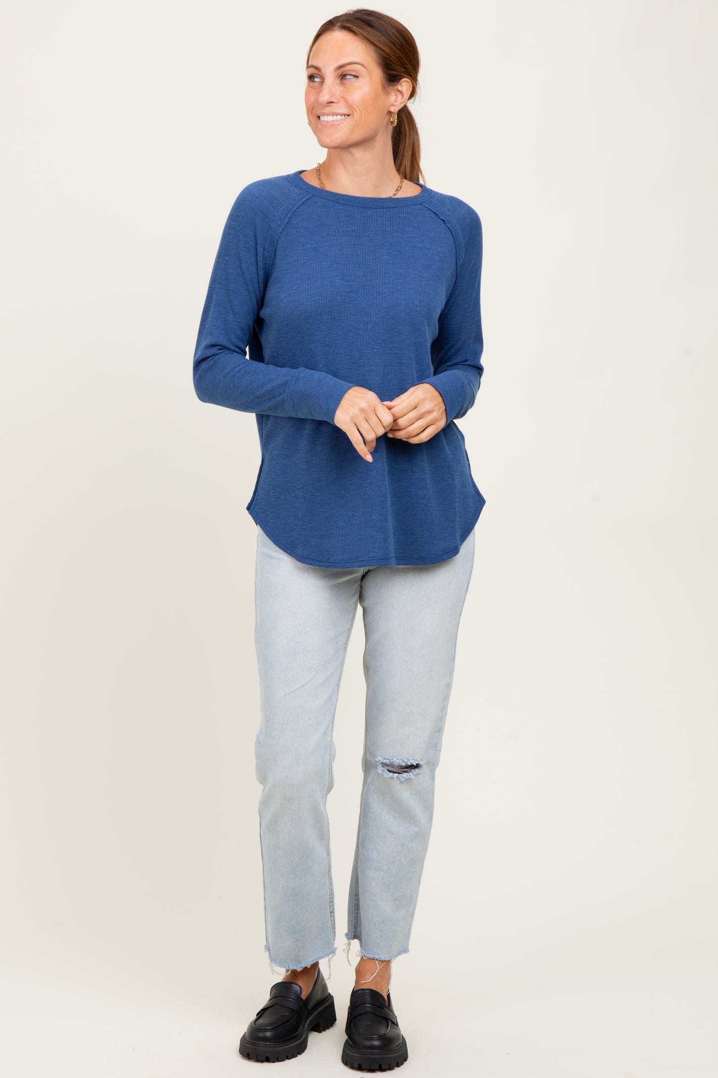 woman wearing a blue long sleeve waffle knit top and light blue ripped jeans
