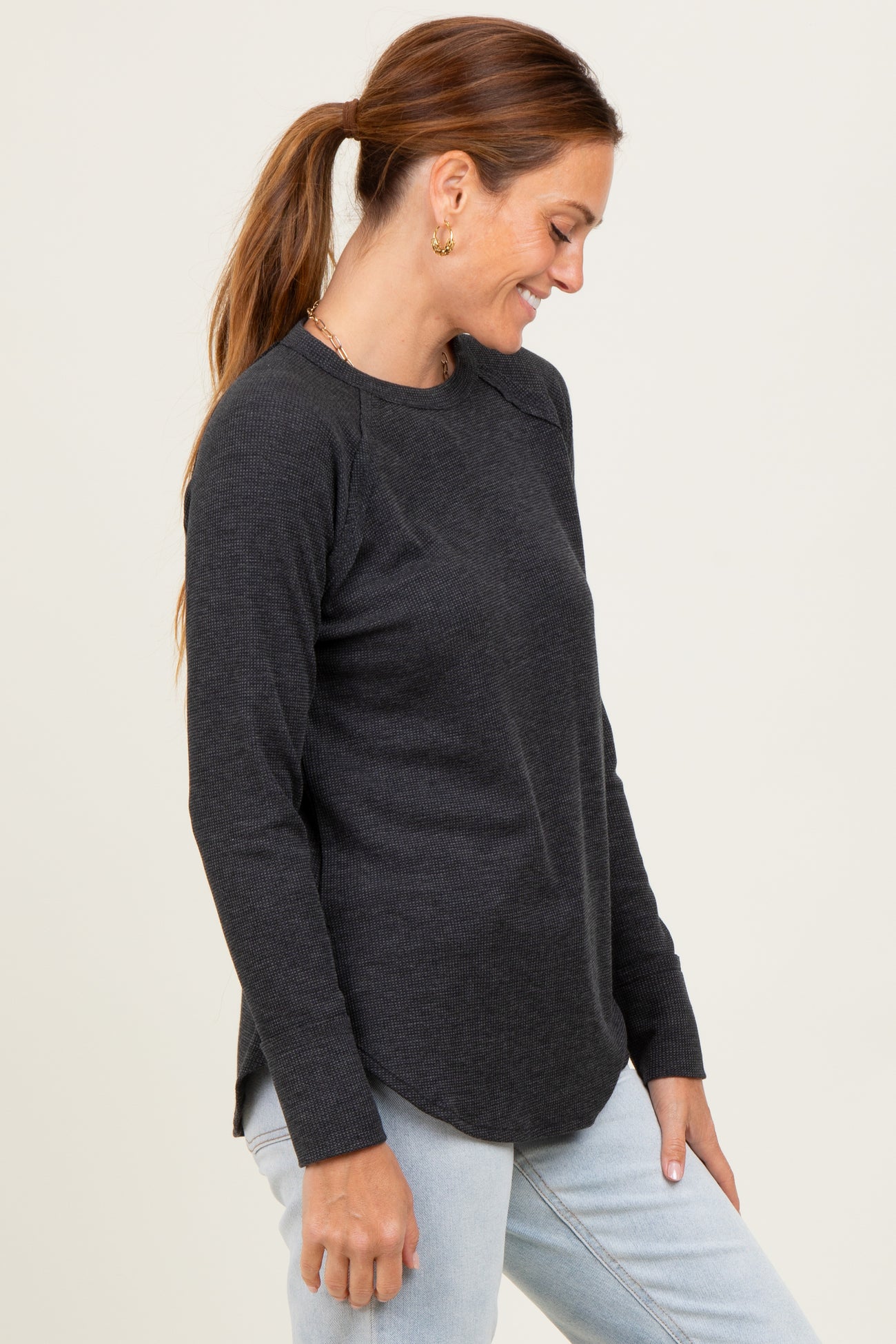 woman wearing a charcoal gray long sleeve ribbed top with side slits and a relaxed fit