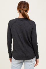 woman wearing a dark gray long sleeve top with a back seam detail and round hemline, seen from the back