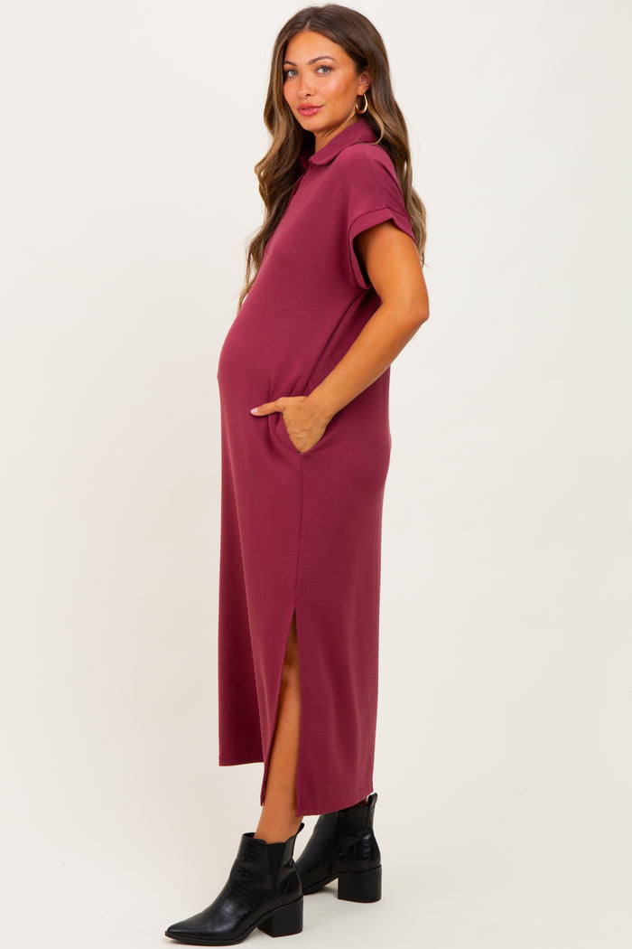 woman wearing a burgundy maternity dress with short sleeves, pockets, and side slits, showing her baby bump