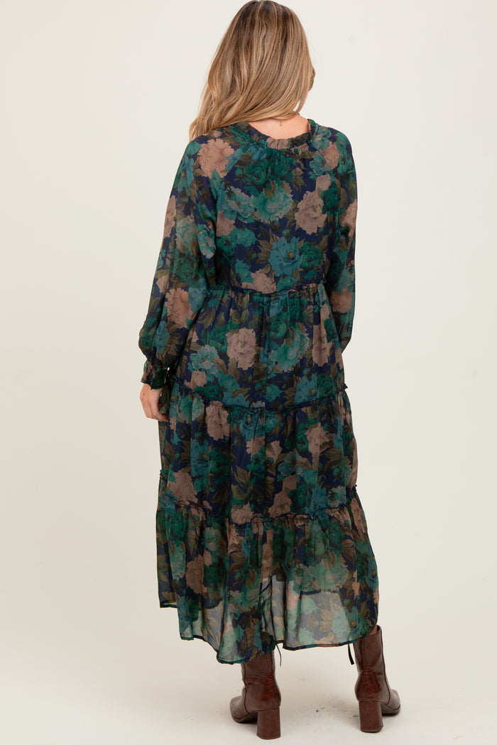 woman wearing a flowy green floral maternity maxi dress with long sleeves and ruffle details, showcasing a baby bump