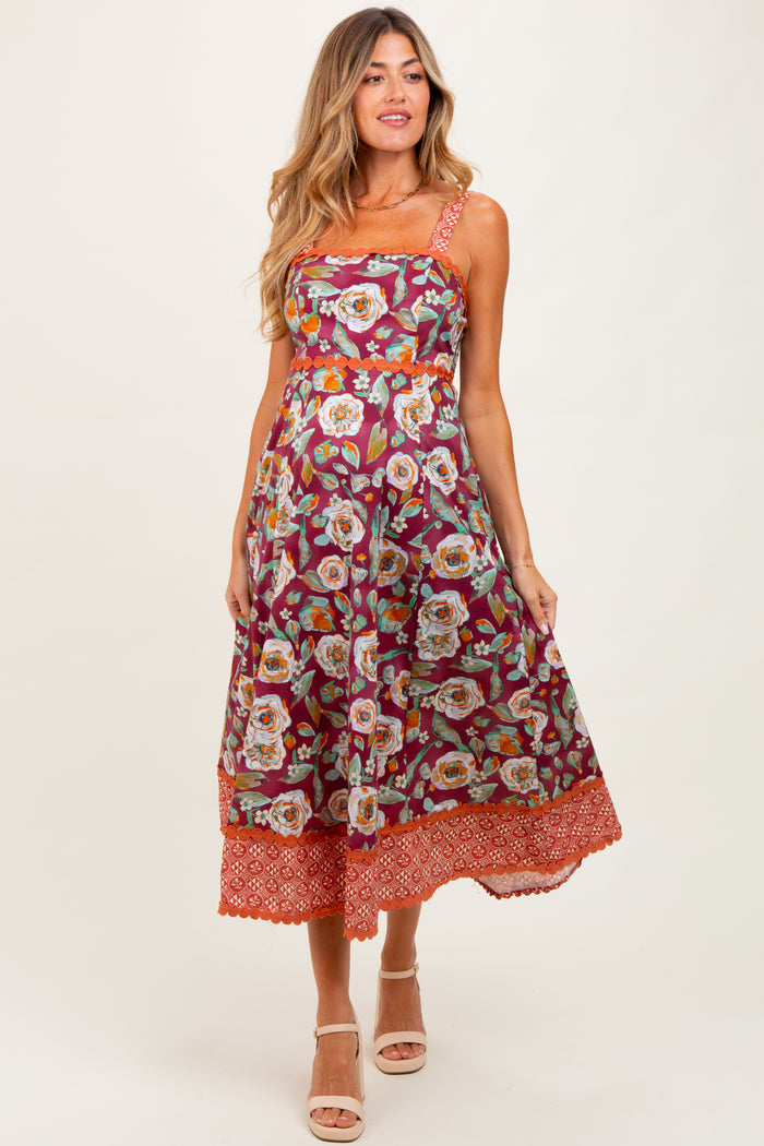 woman wearing a floral burgundy maternity dress with orange trim and an elastic waistband