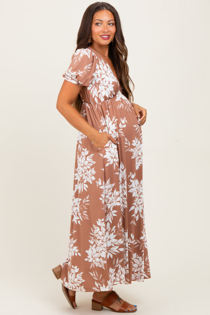 woman wearing a brown floral maternity maxi dress with short sleeves and pockets, showing her baby bump