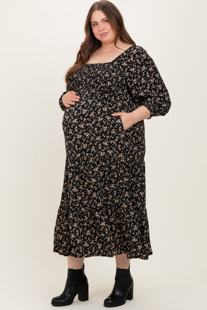 woman wearing a black floral maternity dress with a square neckline and pockets, showing her baby bump