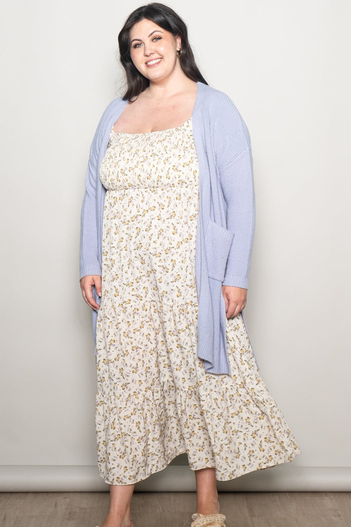 woman wearing a light blue open cardigan over a floral maxi dress in plus size