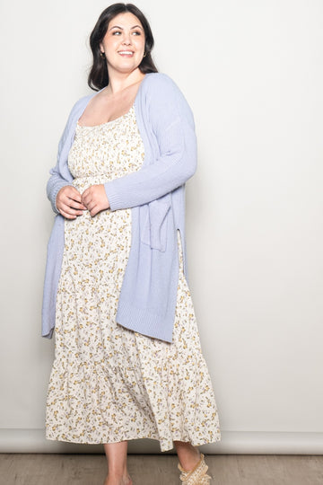 woman wearing a light purple cardigan over a floral maxi dress in a plus size fit