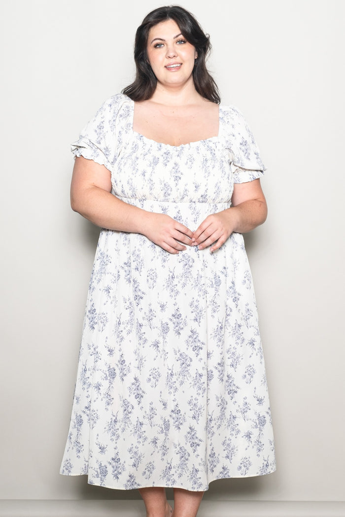 woman wearing a white floral plus-size tea dress with short puff sleeves and a square neckline