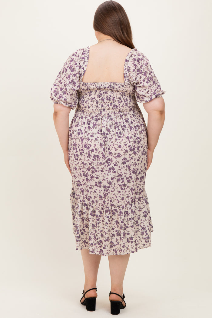 woman wearing a floral maternity plus dress with puff sleeves, featuring a smocked back and ruffled hem