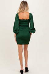 woman wearing a green maternity mini dress with puff sleeves and ruching detail at the back