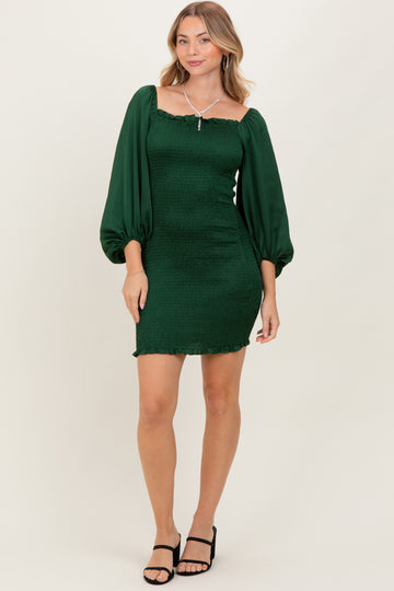 woman wearing a dark green off-the-shoulder mini dress with smocked bodice and puff sleeves