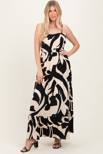 woman wearing a black and beige abstract print maxi dress with spaghetti straps and a tiered hem