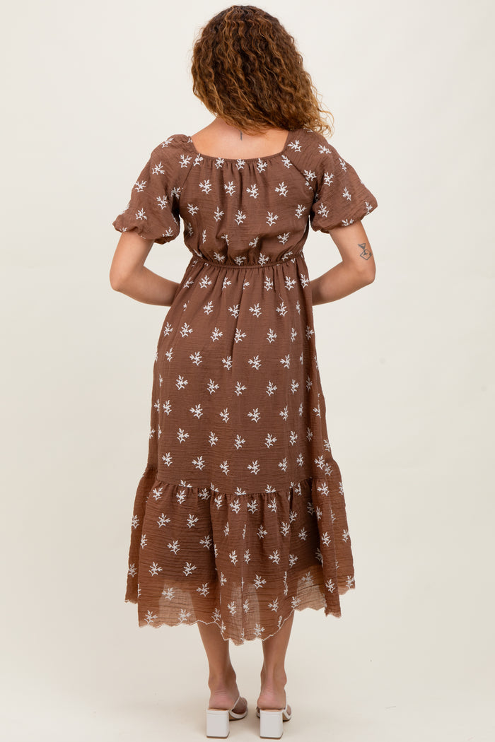 woman wearing a brown floral print maxi dress with short sleeves and a tiered skirt, seen from the back
