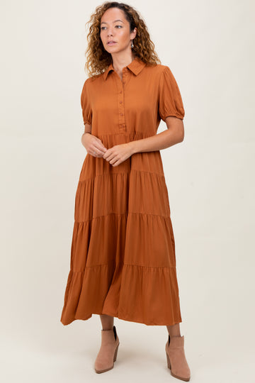 woman wearing a rust-colored tiered maxi dress with short puff sleeves and a button-up front