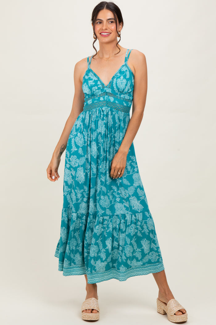 woman wearing a teal floral maxi dress with adjustable straps and a tiered skirt