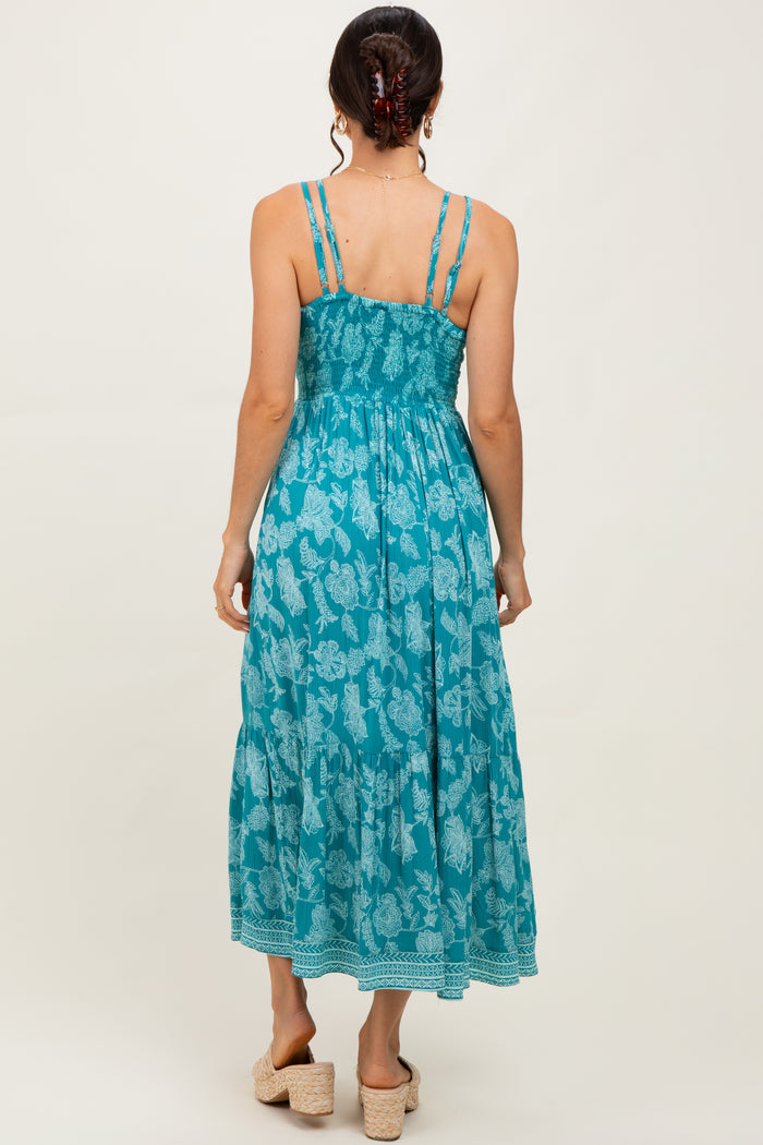 woman wearing a teal floral maxi dress with adjustable straps and a smocked back
